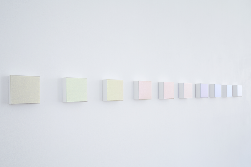 Art display of pastel blocks hanging in a straight line