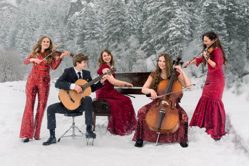 Jenny Oaks Baker and her family perform on their instruments in a snow covered field.