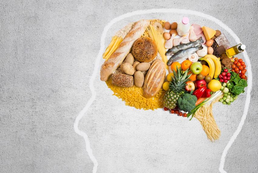 Various food items collected together to form the shape of a brain within the outline of a head