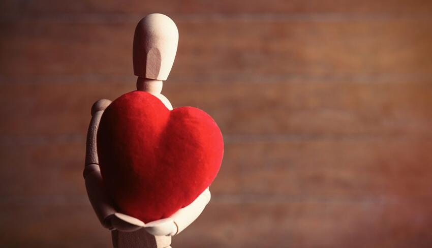 Wooden human figure holding a felt heart