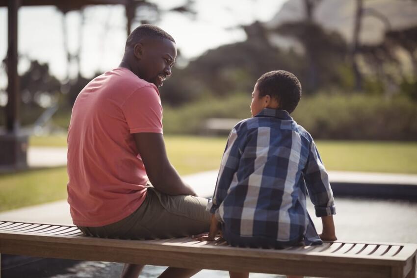 A man and boy sitting together at a park table