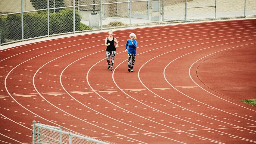 Two women walking on a track field