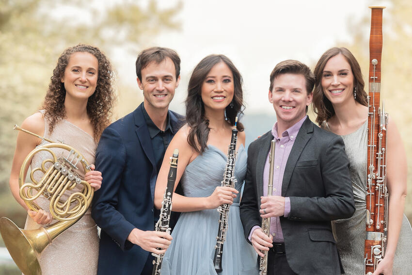 The artists from WindSync are outside and holding their instruments in this promotional photo. From left to right, they are Anni Hochhalter, Graeme Steele Johnson, Emily Tsai, Garrett Hudson, and Kara LaMoure.