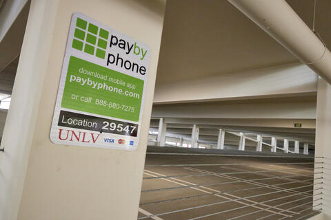 Green and white pay by phone sign in a parking garage.