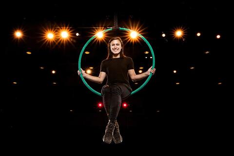 Woman sits on a hoop inside of a theater