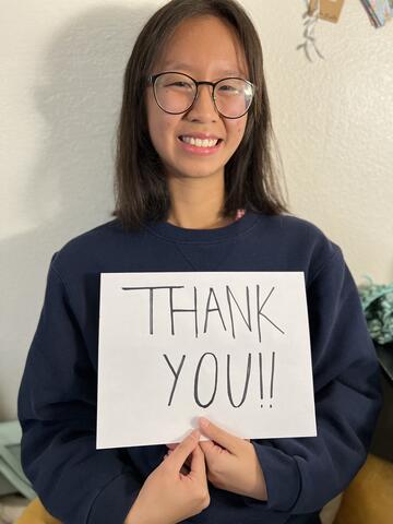 college student in glasses holds sign that says thank you