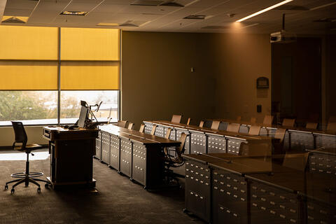 A classroom with rows of desks and a front table