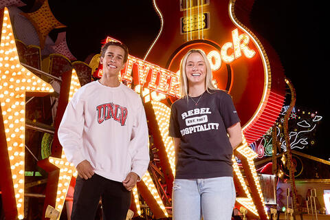 Two students standing in front of neon signs.