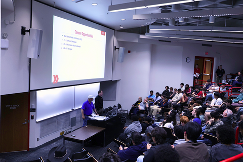 A classroom filled with students sitting down on desks
