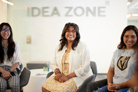 Three people sit in chairs in a group setting.
