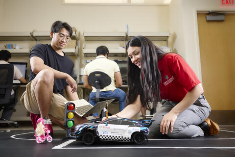 2 students working on coding a toy car