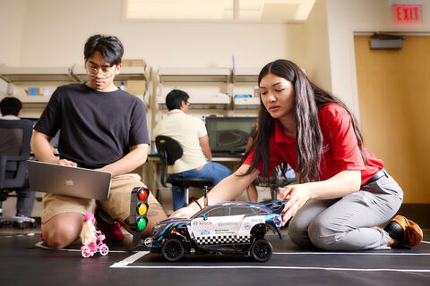 Students working on a remote controlled car in a classroom.