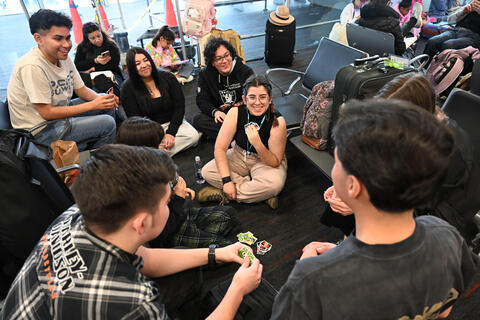 Classmates play cards to pass the time during the Miami airport delay.