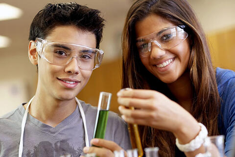 Two students smiling while doing lab work