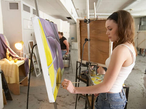 A student painting on a canvas