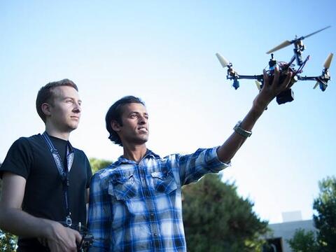 Two male students - one is holding a drone in his left hands