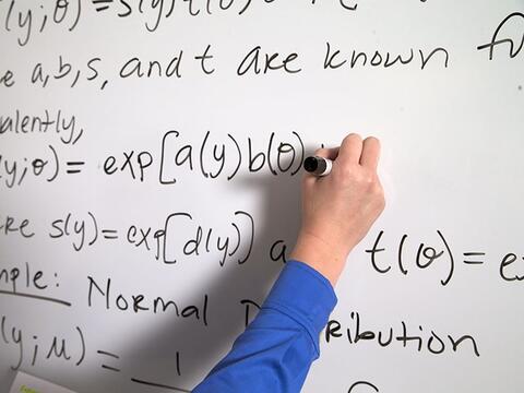 A person writing an equation on the whiteboard