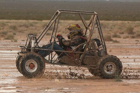 Person driving a vehicle through mud.