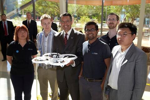 Group posing in front of a drone.