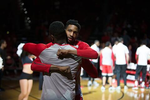Two male basketball players hugging each other.