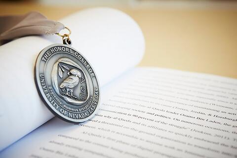 An honors medallion resting on an open textbook.