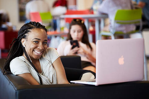 A woman smiling in front of her laptop