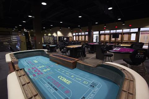 Large room with various tables for gambling including craps and a few slot machines