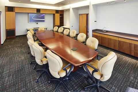 Large wood conference table surrounded by large plush office-style chairs